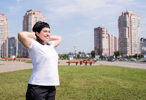 Sport and fitness. Senior sport. Active seniors. Smiling senior woman warming up before training outdoors in the park on urban background