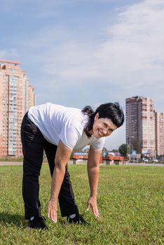 Sport and fitness. Senior sport. Active seniors. Smiling senior woman warming up stretching outdoors in the park