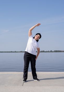 Sport and fitness. Senior sport. Active seniors. Active and happy senior woman exercising near the riverside