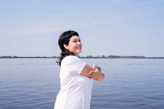 Sport and fitness. Senior sport. Active seniors. Active and happy senior woman doing stretching near the riverside