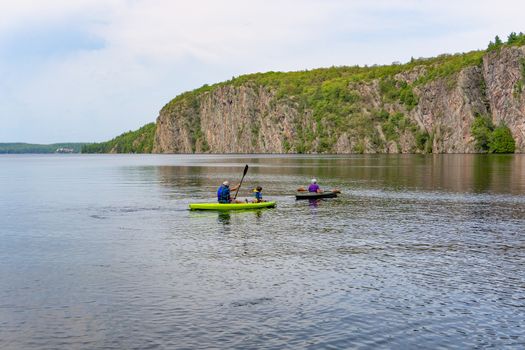 A family in two kayaks float along large rocks along the river