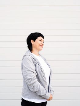 Sport and fitness. Senior sport. Active seniors. Senior woman waring gray jacket standing outdoors on gray solid background