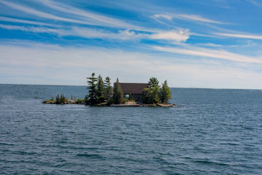 Buildings on an islet in a large lake hidden by large trees and bushes