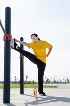 Sport and fitness. Senior sport. Active seniors. Senior woman stretching her legs outdoors on the sports ground