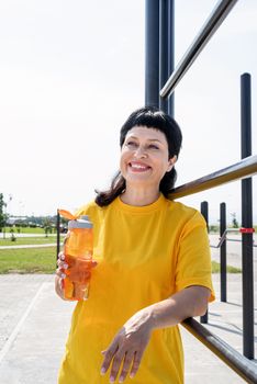 Sport and fitness. Senior sport. Active seniors. Smiling senior woman drinking water after workout outdoors on the sports ground