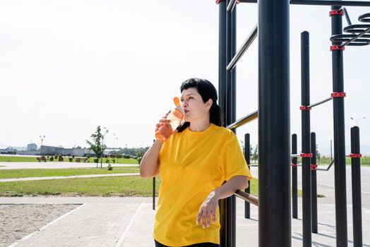 Sport and fitness. Senior sport. Active seniors. Smiling senior woman drinking water after workout outdoors on the sports ground