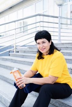 Sport and fitness. Senior sport. Active seniors. Smiling senior woman drinking water after workout outdoors on urban background