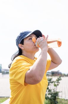 Sport and fitness. Senior sport. Active seniors. Smiling senior woman drinking water after workout outdoors on the sports ground