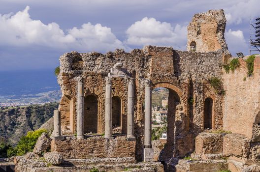 Detail of the stage of the theater of taormina and panorama of sicily background