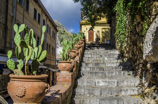 Street of taormina staircase and pots with cactus in the city of taormina