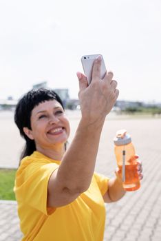 Sport and fitness. Senior sport. Active seniors. Smiling senior sportswoman doing selfie outdoors in the park