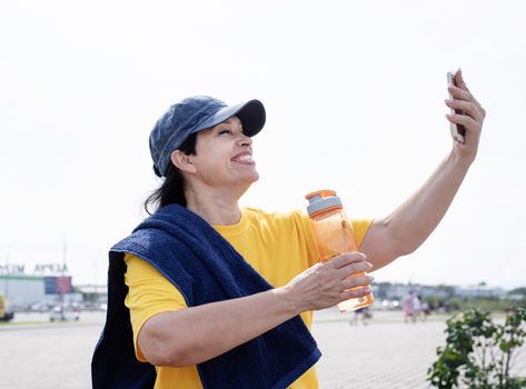 Sport and fitness. Senior sport. Active seniors. Smiling senior sportswoman doing selfie outdoors in the park