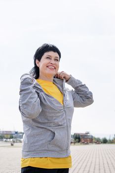 Sport and fitness. Senior sport. Active seniors. Senior woman waring gray jacket on the sports ground