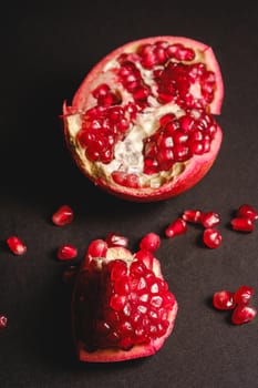 Fresh tasty sweet peeled pomegranate with red seeds on dark background