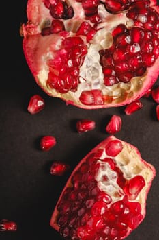 Fresh tasty sweet peeled pomegranate with red seeds on dark background