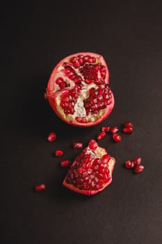 Fresh tasty sweet peeled pomegranate with red seeds on dark background