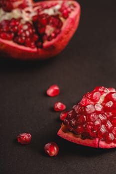 Fresh tasty sweet peeled pomegranate with red seeds on dark background