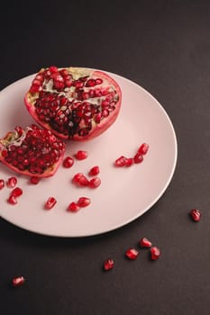 Fresh tasty sweet peeled pomegranate with red seeds on dark background