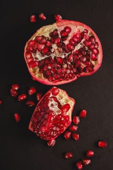 Fresh tasty sweet peeled pomegranate with red seeds on dark background