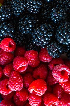 Close-up of raspberry and black mulberry berries split frame. Summer vitamins, sweet berries