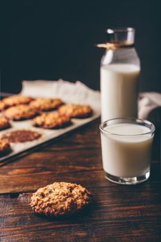 Oatmeal Cookies with Raisins and Glass of Milk for Breakfast. Some Cookies on Parchment Paper with Bottle on Backdrop. Vertical Orientation.