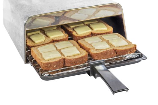 Horizontal shot of a toaster tray with four pieces of buttered wheat bread going into a toaster.