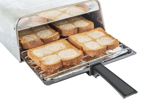 Horizontal shot of a toaster tray with four pieces of buttered wheat bread coming out of a toaster.