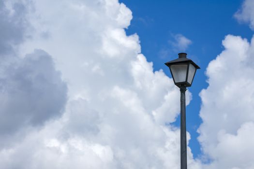 Horizontal shot of a lamppost against a blue cloudy sky.