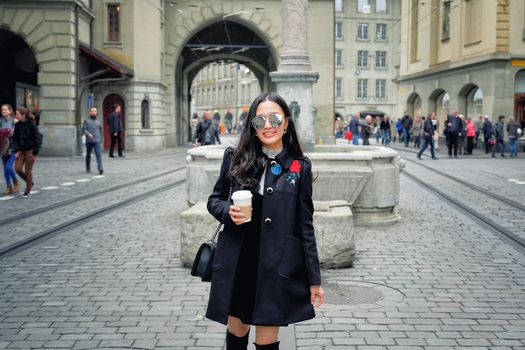 Beautiful young woman in the street drinking morning coffee