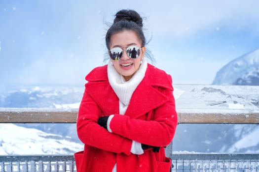 Beautiful young woman playing with snow in fur red coat outdoors