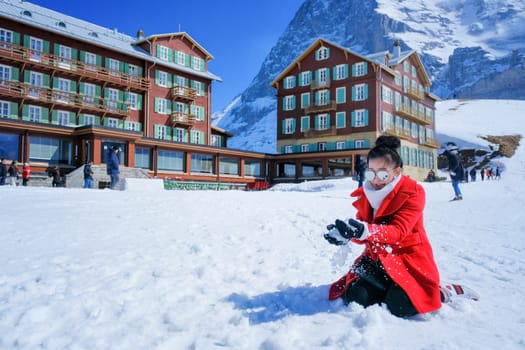 Beautiful young woman playing with snow in fur red coat outdoors