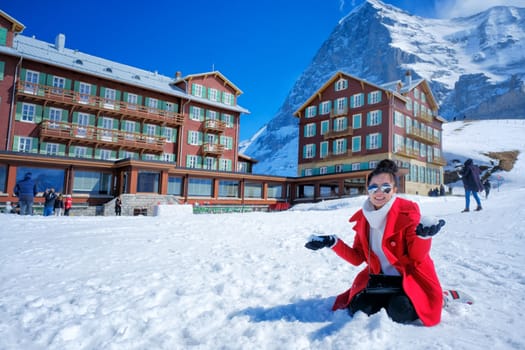 Beautiful young woman playing with snow in red coat outdoors