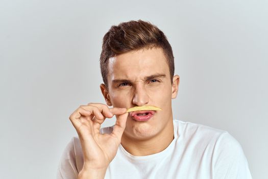 emotional man holding fries calories fast food light background white t-shirt cropped view. High quality photo