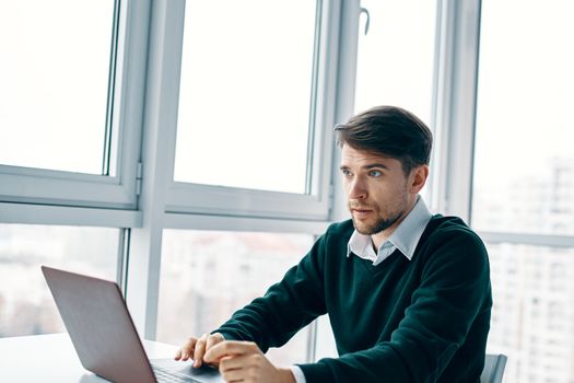 Man typing text on laptop in the office near the window