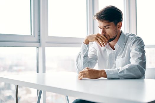 sad man of european appearance at the table indoors at work