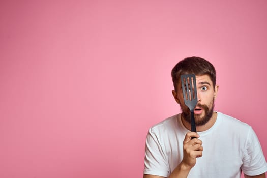 Man with spatula in hands kitchen accessories model emotions pink background cropped view Copy Space. High quality photo