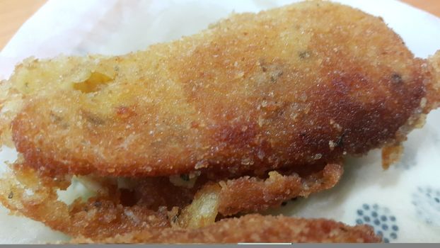 Closeup perspective view of home made spicy and delicious croquettes served in ceramic plate over wooden floor