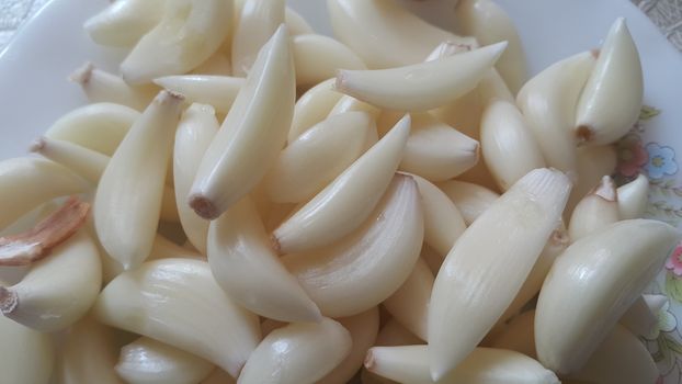 Garlic is aromatic and flavorful herb for consumption and use in spices and for medicinal purposes. Close-up view of dry peeled garlic clove background