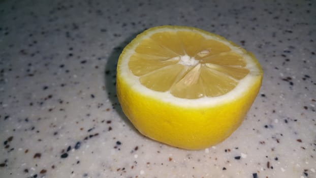 Fresh lemon slices with yellow peelings placed on a grey floor. Top view of fresh juicy lemon slice background