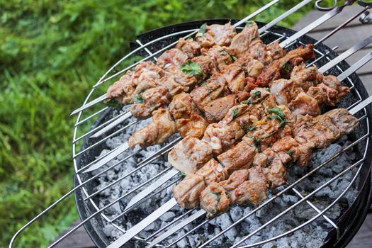 Russian shashlik with skewers on a round grill in Norway.