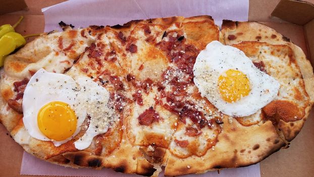 egg and bacon and cheese breakfast pizza in cardboard box