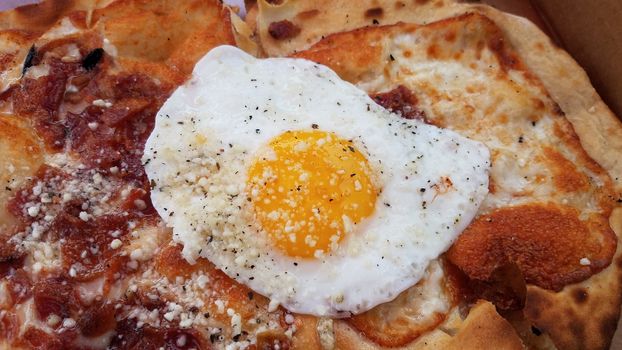 egg and bacon and cheese breakfast pizza in cardboard box