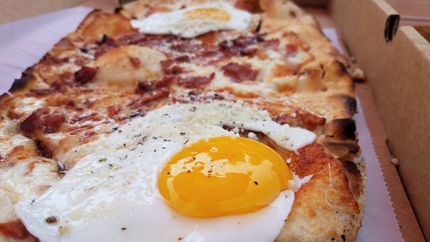 egg and bacon and cheese breakfast pizza in cardboard box