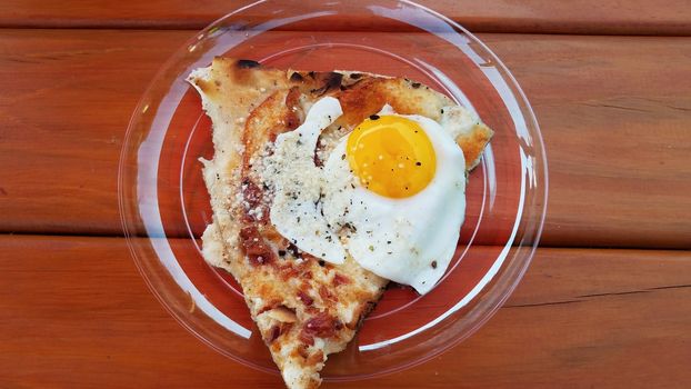 egg and bacon breakfast pizza on plate on wood table
