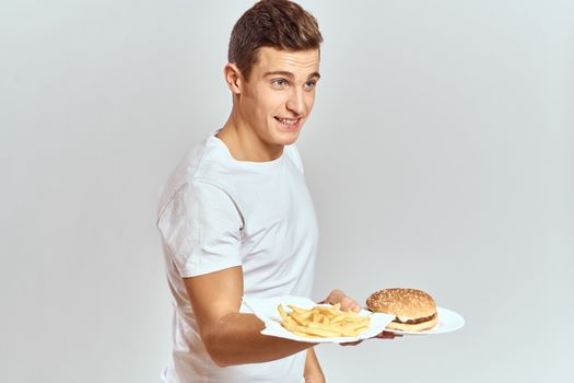 a man with fries and a hamburger on a light background in white t-shirt close-up cropped view Copy Space Model. High quality photo