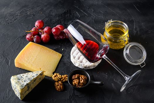 Grapes, red wine, cheeses, honey and nuts side view red merlot wine in glass antipasto.