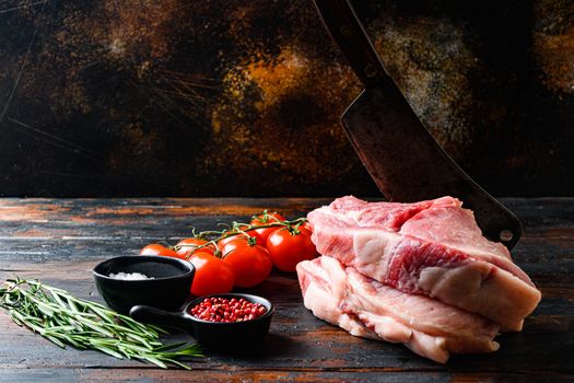 Farm fresh Pork Belly,Raw pork cutlet with oil and spices for grill or cooking on wooden dark planks over rustic background, and chopping cleaver butcher knife, side view spacr for text horisontal.