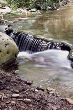 Small waterfall in a mountain river, transparent water, long exposure,