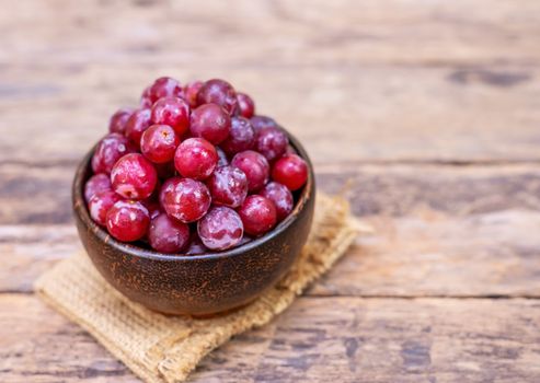 Red grape fruit in wooden bowl on blurred background