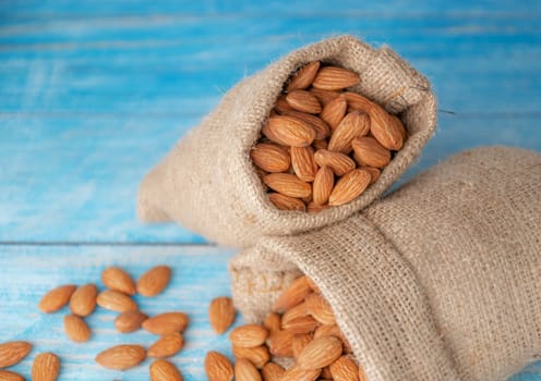 Almond in cloth bag on blurred wooden table background